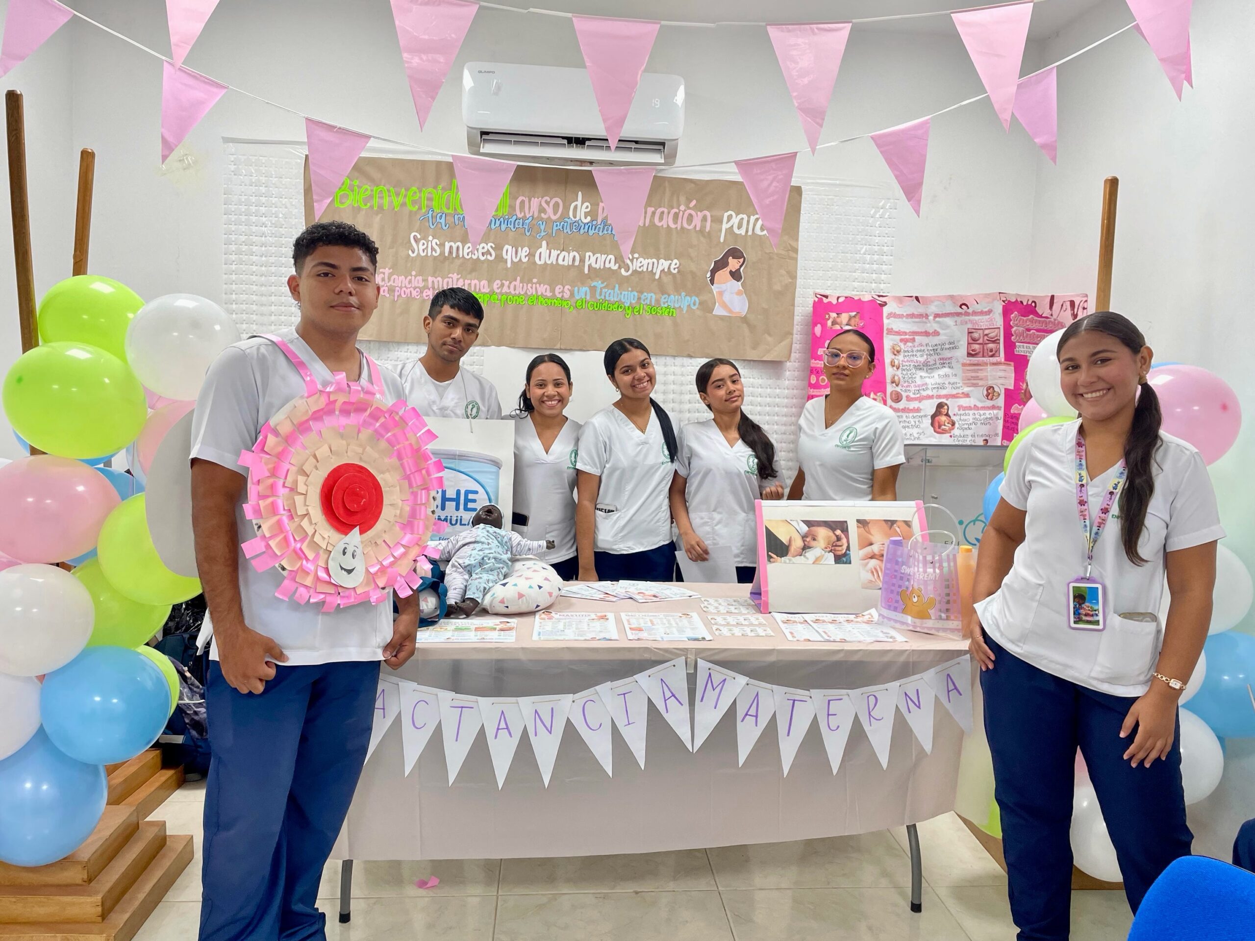 Integrantes del personal de salud posan junto a materiales educativos y una decoración alusiva a la Semana Mundial de la Lactancia Materna.